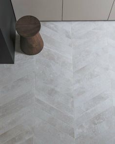 a white tile floor with a wooden stool next to it