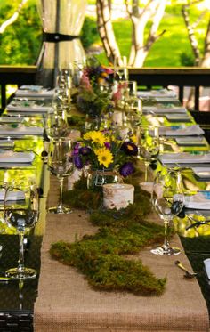 a long table with moss covered place settings