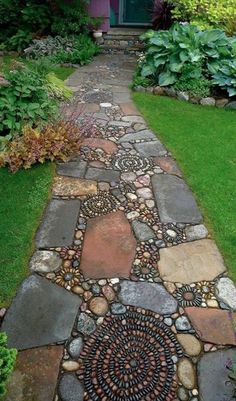 a walkway made out of rocks and stones in front of a purple house with green doors