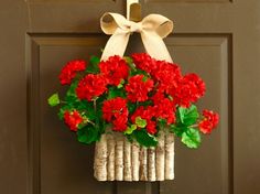 a bunch of red flowers in a basket hanging on a door