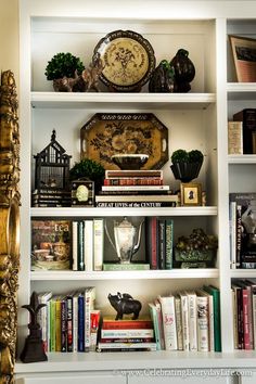 a bookshelf filled with lots of books next to a clock and other items