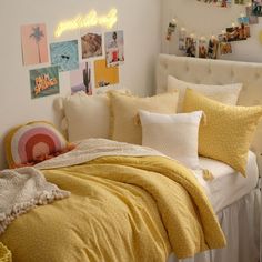 a bed with yellow comforter and pillows in a bedroom next to a white headboard