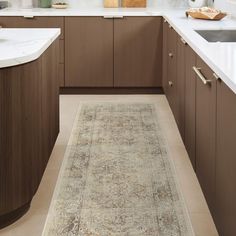 a beige rug is in the middle of a kitchen with brown cabinets and white counter tops