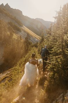 a bride and groom walking up a trail in the mountains