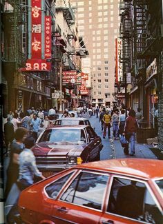 a busy city street filled with lots of cars and people walking on the side walk