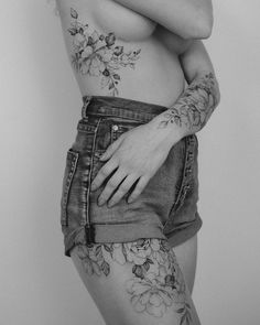 a woman with tattoos on her arms and chest is posing for the camera while wearing denim shorts