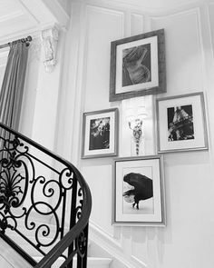 black and white photograph of stairs with pictures on the wall above them, along with an iron handrail