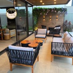 an outdoor living area with black wicker furniture and plants on the wall behind it