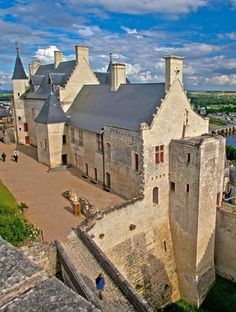 an aerial view of a castle with people walking on the walkway and water in the background