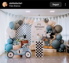 a birthday party with balloons and mickey mouse decorations on the wall, along with an old race car