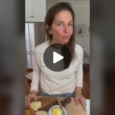 a woman standing in front of a cutting board with bread and butter on it, making a face