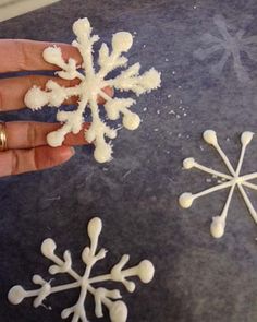 someone is making snowflakes out of white powder on a counter top with their fingers