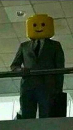 a man in a suit and tie standing on an escalator with a lego head