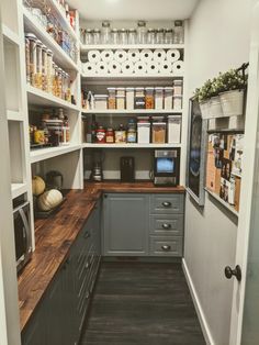 a kitchen with gray cabinets and wooden counter tops in the center is an open pantry