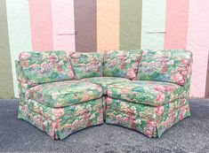 a green floral couch sitting in front of a wall with pink and green striped walls