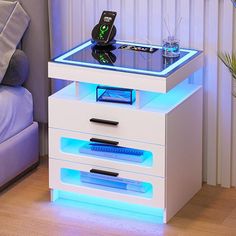 a white night stand with blue lights on it and a remote control in the drawer