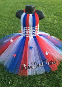 a red, white and blue tutue with stars on the top is sitting in grass