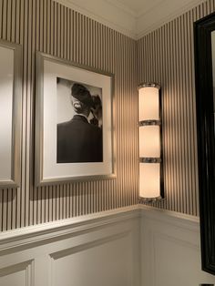 a bathroom with two framed pictures on the wall next to a mirror and light fixture