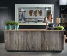 a woman standing behind a counter with potted plants