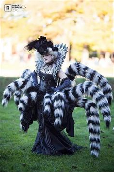 a woman dressed in black and white is sitting on the grass