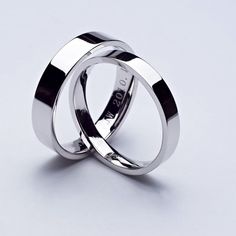 two silver wedding rings sitting on top of each other