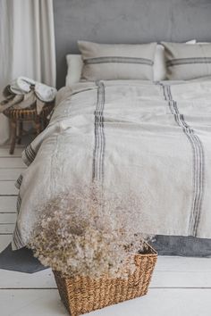 a bed with white linens and a wicker basket on the floor next to it