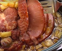 ham and potatoes are being cooked in the crock pot with a fork on top