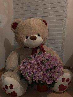 a large teddy bear sitting next to a bouquet of flowers