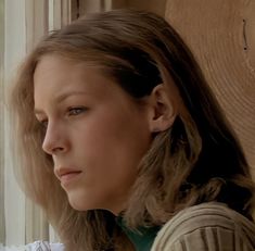 a woman with long hair looking out the window