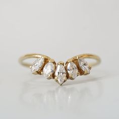 three stone gold ring on white surface with reflection in the middle and small diamond stones at each end