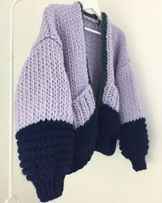 a purple and black sweater hanging on a white wall