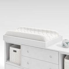 a white crib with drawers and baskets next to it