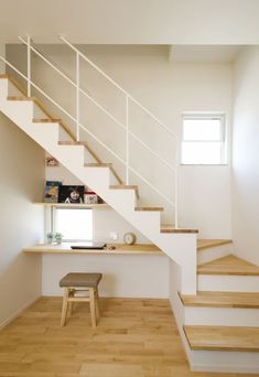 there is a white stair case next to the desk in this room with wood flooring