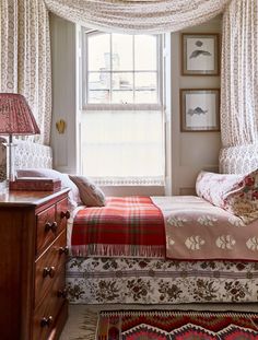 a bed sitting under a window next to a dresser