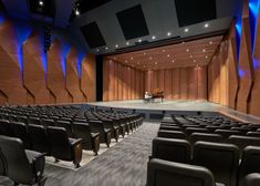 an empty auditorium with rows of seats and a piano on the stage in front of it