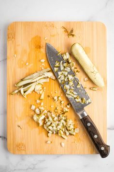 chopped up onions on a cutting board with a knife next to it and an eggplant