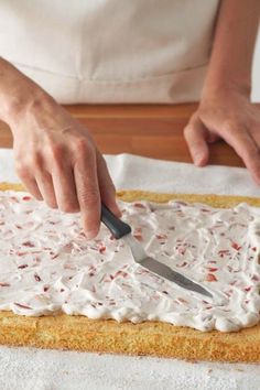 a person is spreading icing on a cake with a knife and napkin in front of them