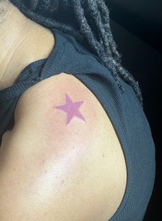 a person with a pink star tattoo on their back shoulder and arm, looking at the camera