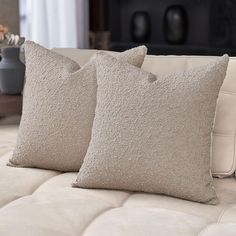 two pillows sitting on top of a white couch