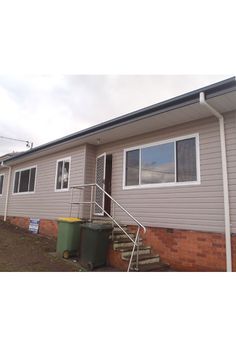 a small house with stairs leading up to the front door and windows on each side