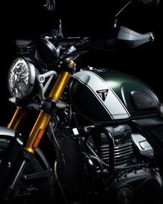 the front end of a green motorcycle on a black background with gold and silver accents