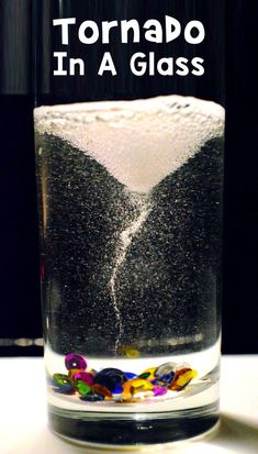 a glass filled with water and black sand