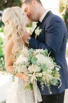 a bride and groom kissing in front of trees