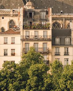 an apartment building with many windows and balconies on the top floor, surrounded by trees