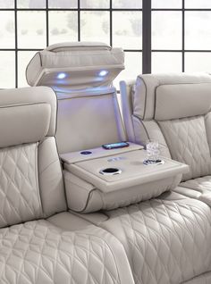 the back seat of a white leather couch with an electronic device on it's center console