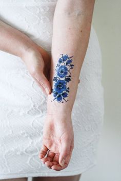 a woman's arm with a blue flower tattoo on her left forearm and wrist