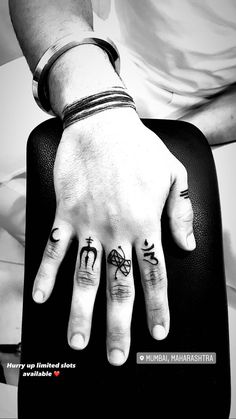 two people with matching tattoos on their fingers, one holding a suitcase and the other sitting down