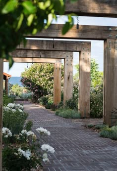 the walkway is lined with white flowers and wooden posts, along with an arbor in the background