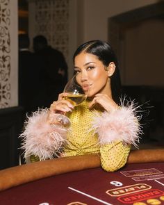 a woman sitting at a casino table drinking wine