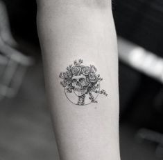 a skull with roses tattoo on the arm